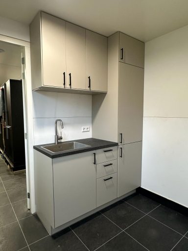 Moderne keuken met grijze kasten en een spoelbak in een minimalistische ruimte.