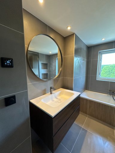 Badkamer renovatie in Nuland Moderne badkamer met grote spiegel, wastafel en bad in neutrale tinten.