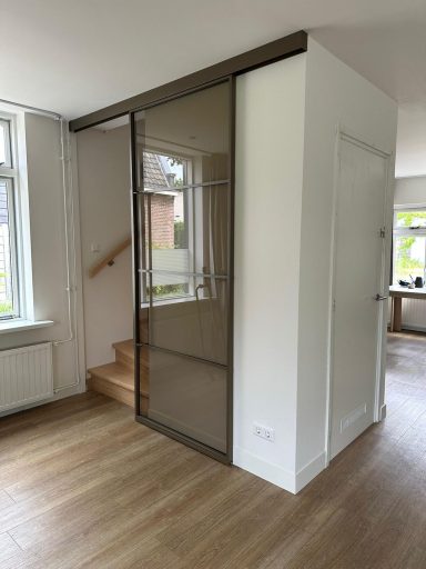 Moderne ruimte met glazen wand en houten trap, helder en minimalistisch interieur.