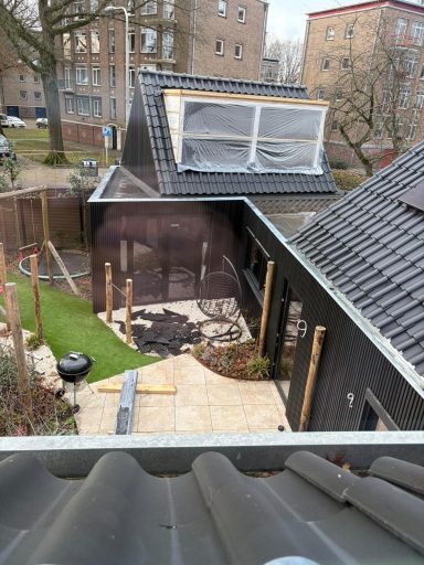 Dakopbouw met dakkapel en gevelbekleding in Tilburg Bovenaanzicht van een huis in aanbouw met een tuin en zwart uitgeslagen gevel.