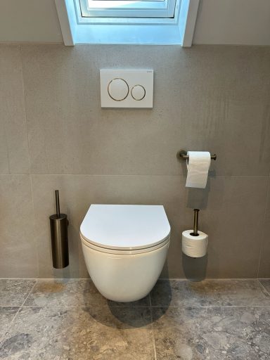 Witte toiletemmer met wandbevestiging, toiletpapierhouder en glazen venster boven.