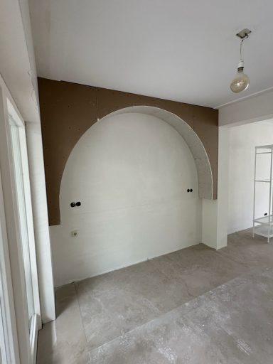 Lege muur met een grote ronde uitsparing aan de bovenkant en betonvloer.