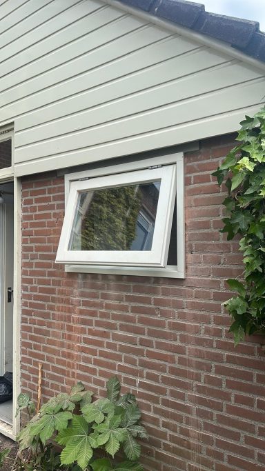Kozijnplaatsing in Zaltbommel Een deel van een huis met een draaikiepraam aan een bakstenen muur.