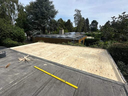 Garage dak in Vlijmen Op een plat dak ligt een houten ondergrond, omgeven door een groene omgeving.