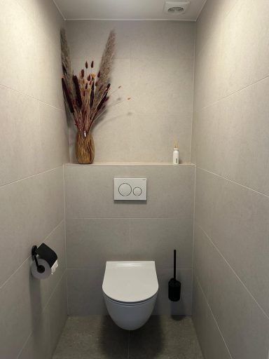 Nieuwbouw toilet in Maliskamp Moderne toiletruimte met wandcloset, toiletborstel en gedecoreerde vazen.