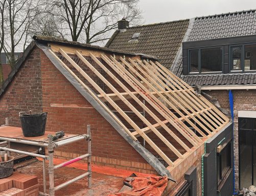 Schilddak in Tilburg Dakconstructie met houten latten en een deel van een muur in aanbouw.