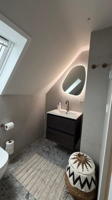 Moderne badkamer met een wastafel, spiegel en beige vloerkleed. Minimalistische inrichting.