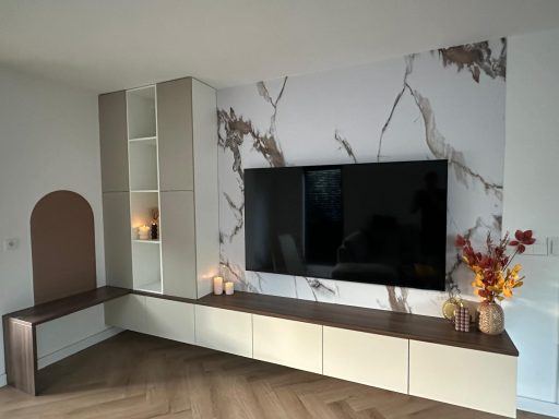 Moderne woonkamer met een tv, marmerwand en decoratieve elementen.